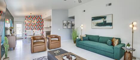 A modern living room with a green sofa, leather armchairs, a coffee table, and a ceiling fan.