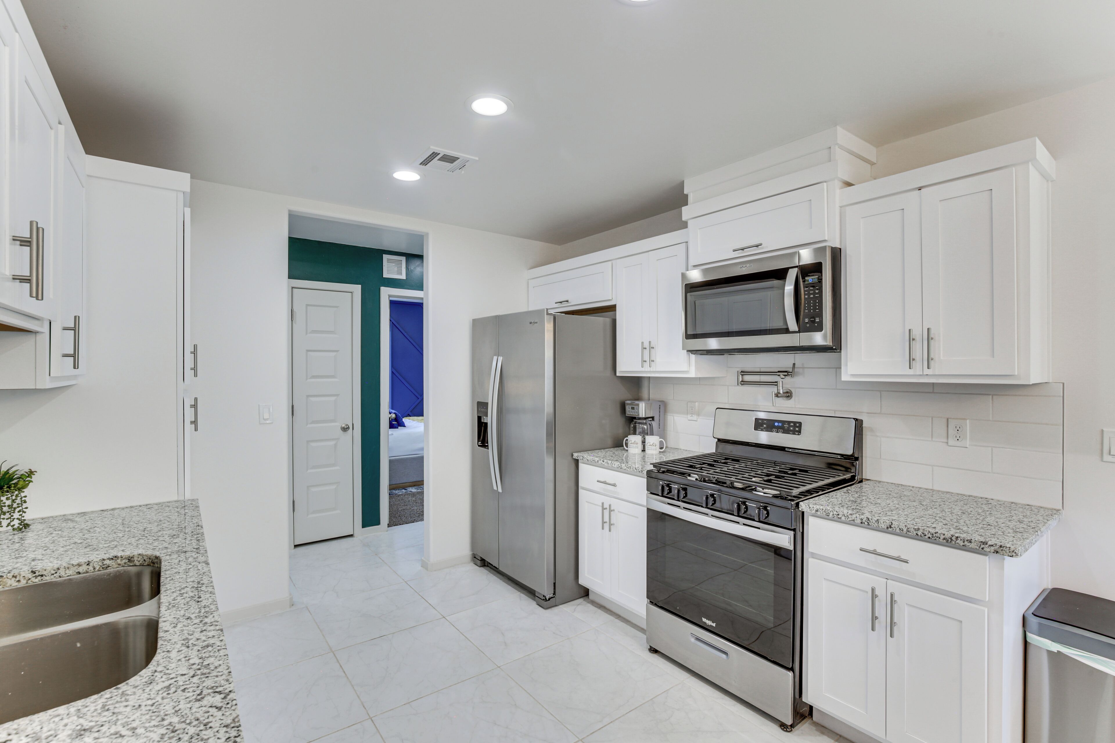 A modern kitchen with white cabinets, stainless steel appliances, and a granite countertop.