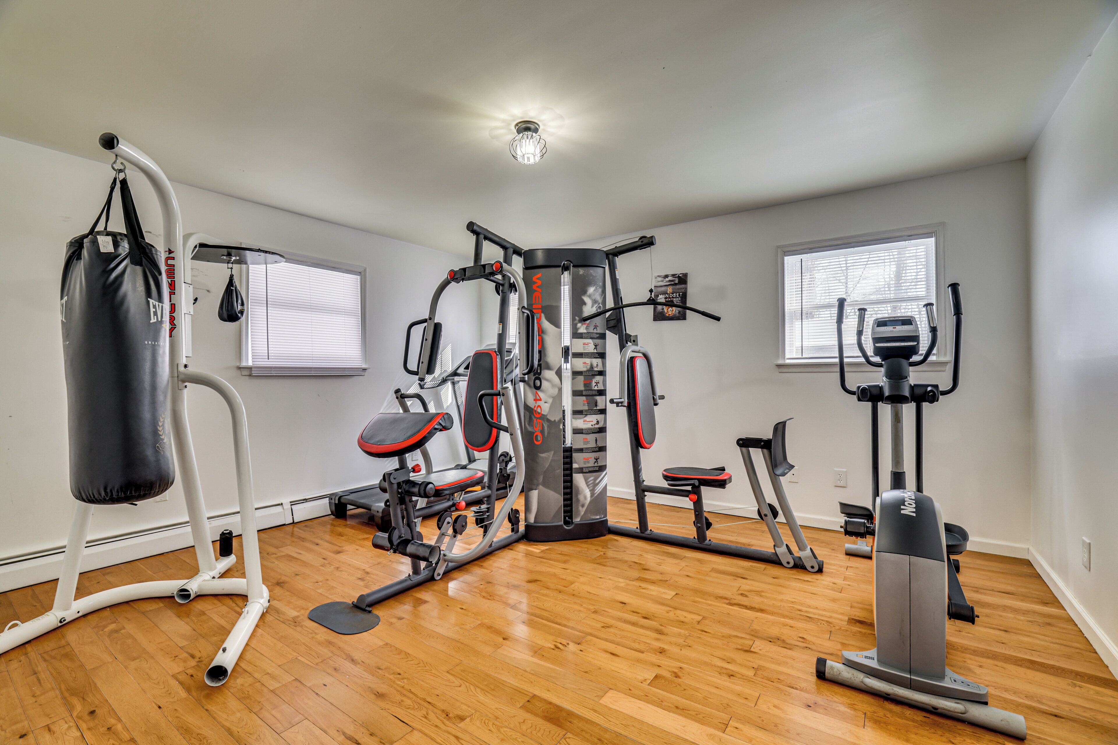 A home gym with various exercise equipment, including a punching bag, weight machines, and a stationary bike.