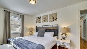 Una camera da letto con un letto, comodini, una panca e opere d'arte alle pareti.
