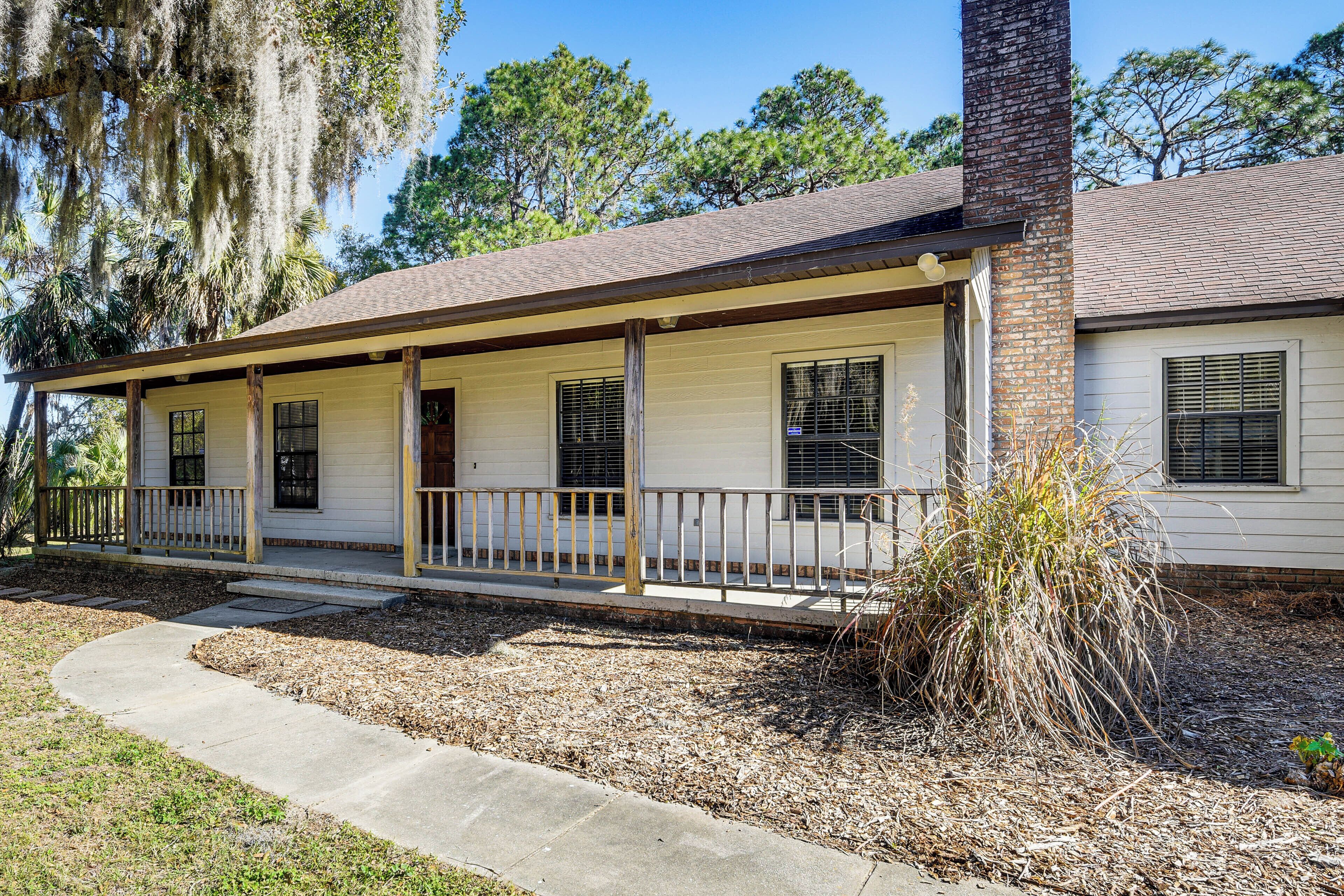A single-story house with a porch, a chimney, and a well-maintained lawn.