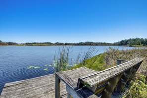A wooden pier extending into a calm lake with lily pads, surrounded by dense vegetation and trees. - Lake Smith Getaway w/ Dock: Families Welcome! (Umatilla)
