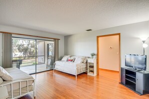 A bedroom with a bed, a TV stand, and a sliding glass door leading to a balcony. - Lake Smith Getaway w/ Dock: Families Welcome! (Umatilla)