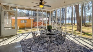 A covered patio with a table and chairs, a ceiling fan, and a view of a lake and trees. - Lakefront Guntersville Base: Boat Parking & Power! (Scottsboro)