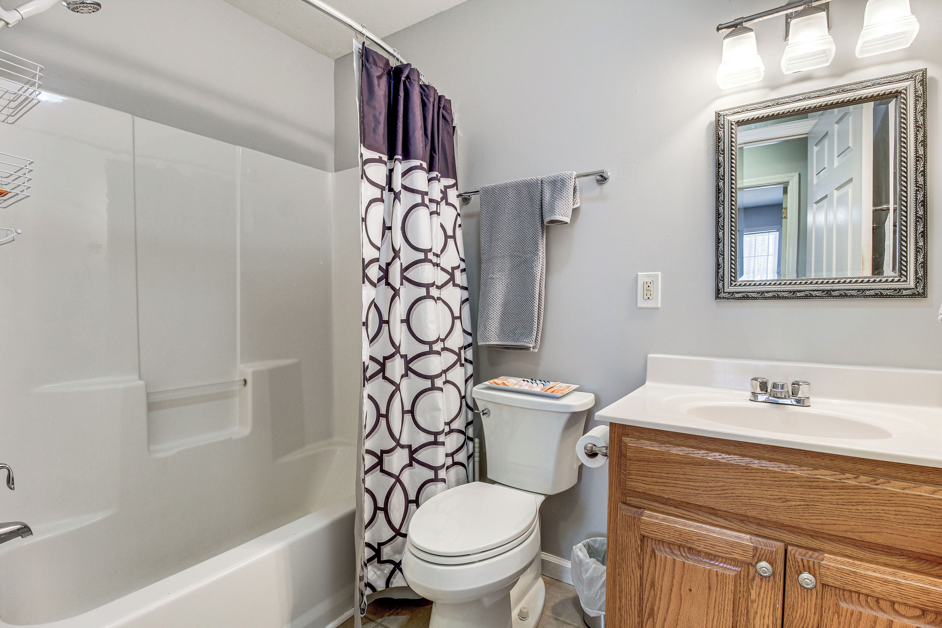 Une salle de bain équipée d’une baignoire, de toilettes, d’un meuble-lavabo et d’un rideau de douche.