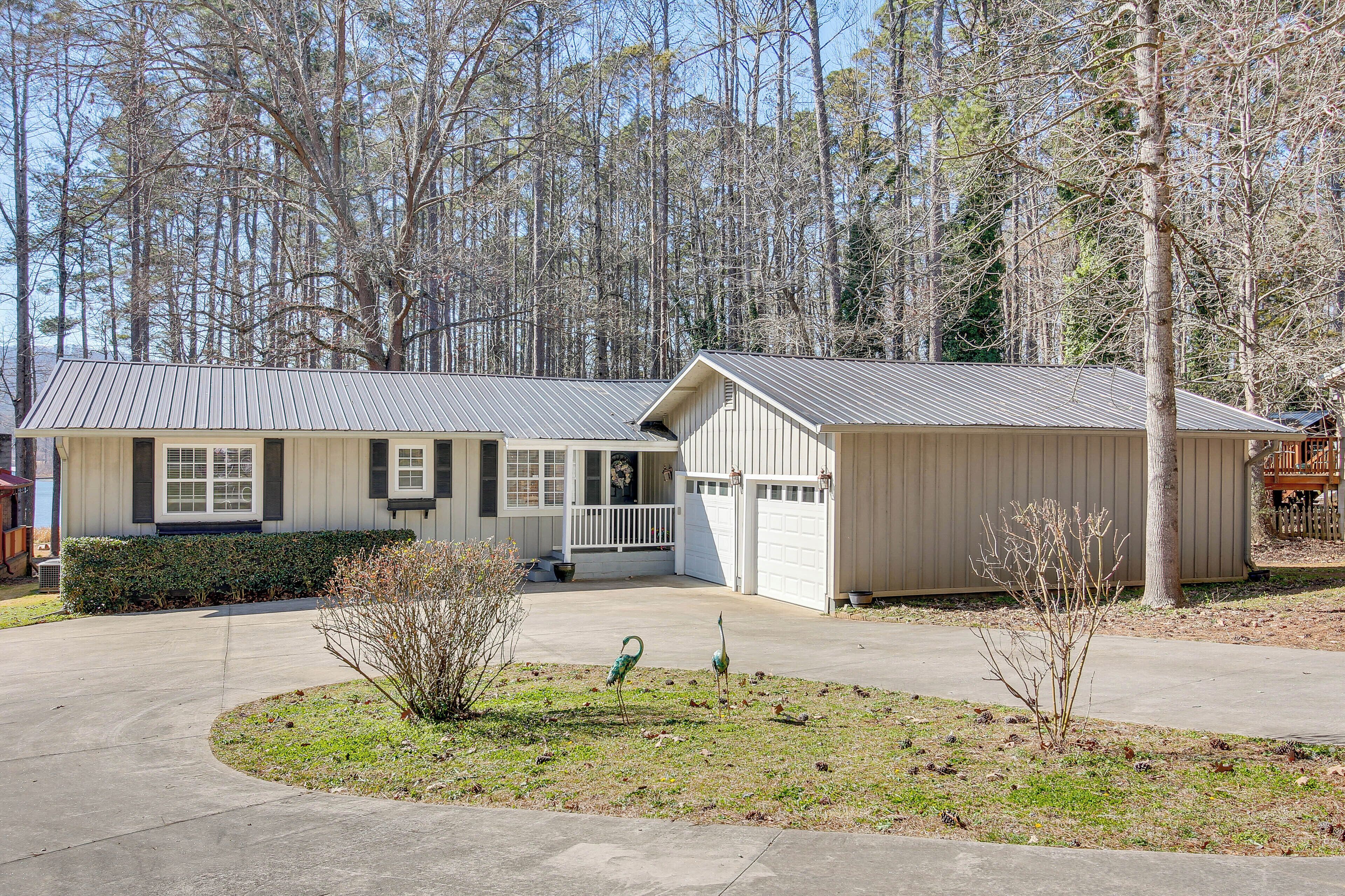 A two-story house with a garage, a front porch, and a small front yard with a tree and a bird sculpture.