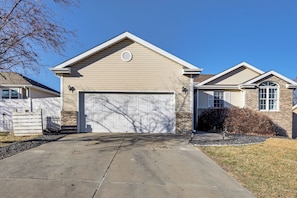 A single-story house with a beige exterior, a garage door, and a small front yard with a tree and a bush. - Spacious & Family Friendly! Lincoln Home w/ Deck (Lincoln)