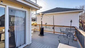 Une terrasse avec du mobilier d’extérieur, une poubelle et un bâtiment à la façade blanche.