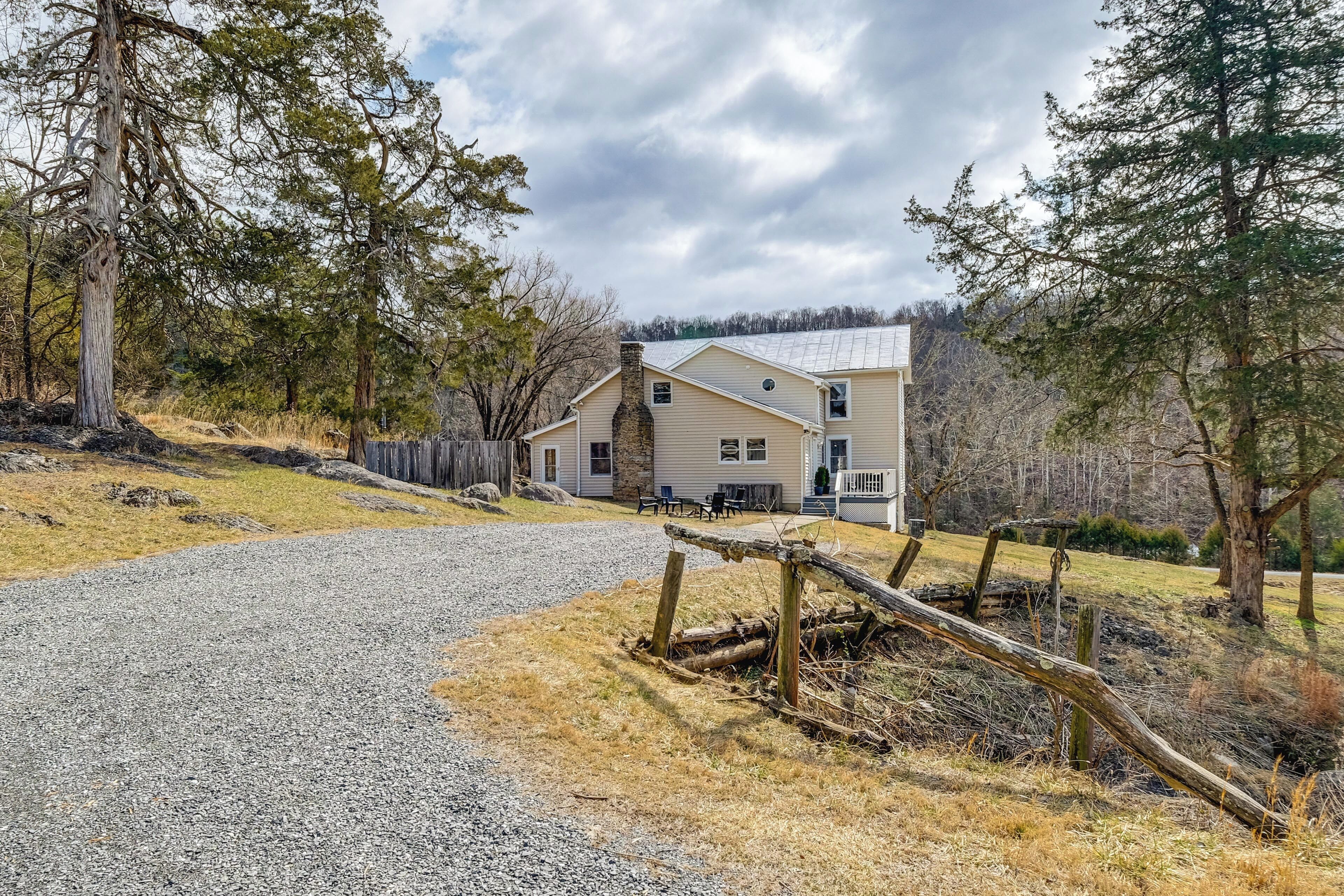 A two-story house with a gravel driveway and a wooden fence.
