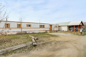 A building with a long, single-story structure, a covered garage, and a gravel driveway. - Walk to Loop Trail! East Wenatchee Basecamp (East Wenatchee)