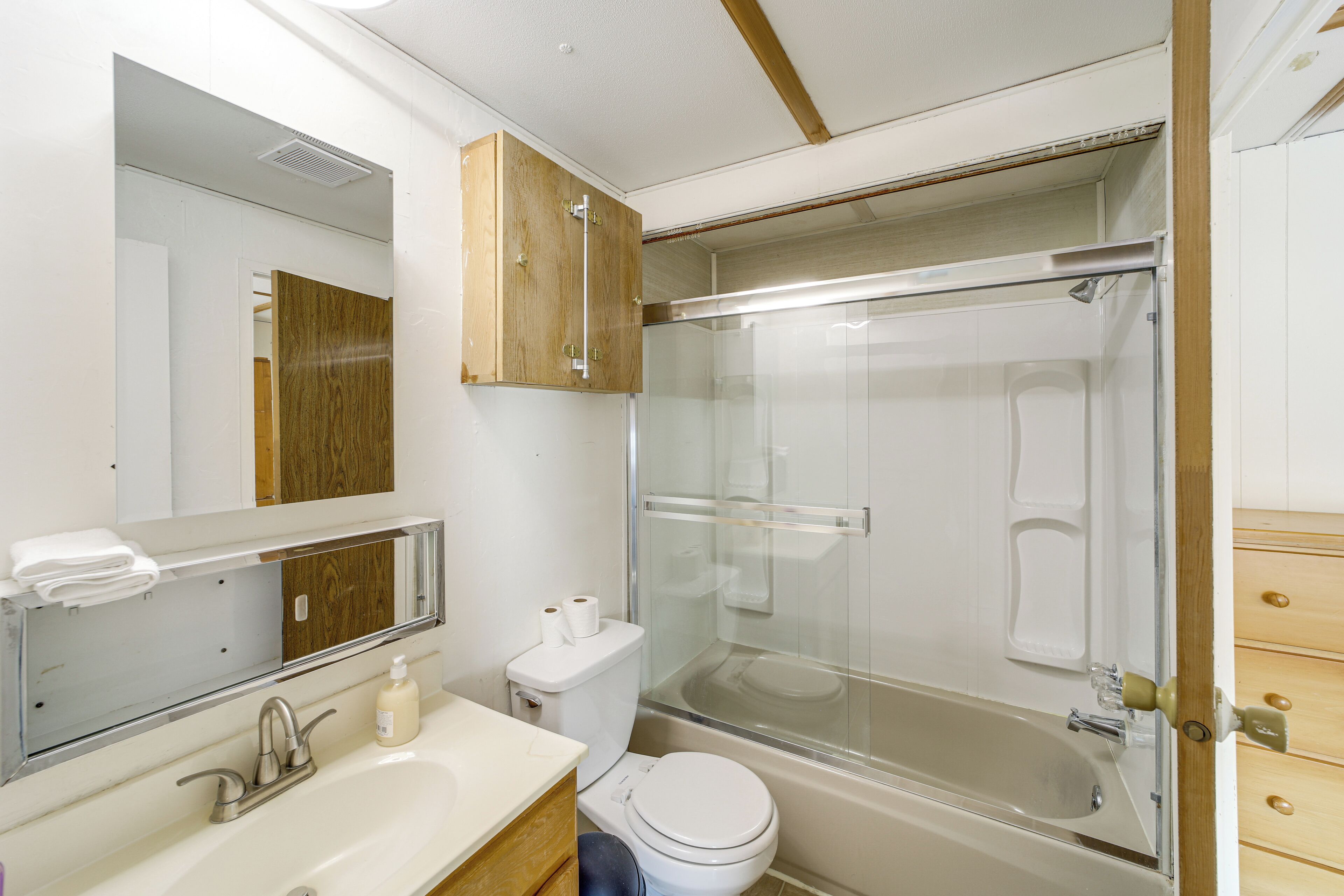 Une salle de bain équipée de toilettes, d’un lavabo, d’un miroir et d’une cabine de douche.