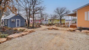 A gravel driveway leading to a row of colorful mobile homes with a clear sky above. - Peaceful Tiny Home Getaway Near Bowie Trade Days (Bowie)