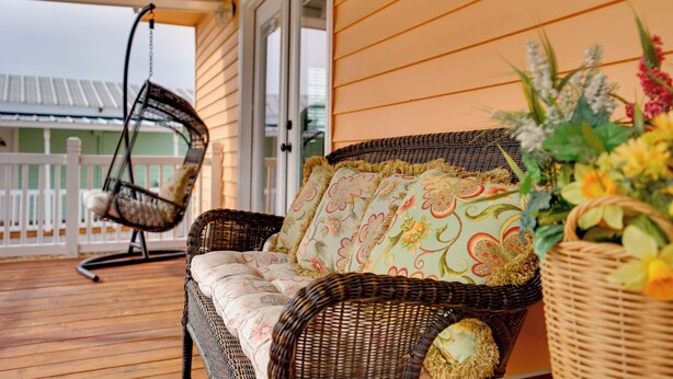 A wicker sofa with floral cushions on a wooden deck. - Peaceful Tiny Home Getaway Near Bowie Trade Days (Bowie)
