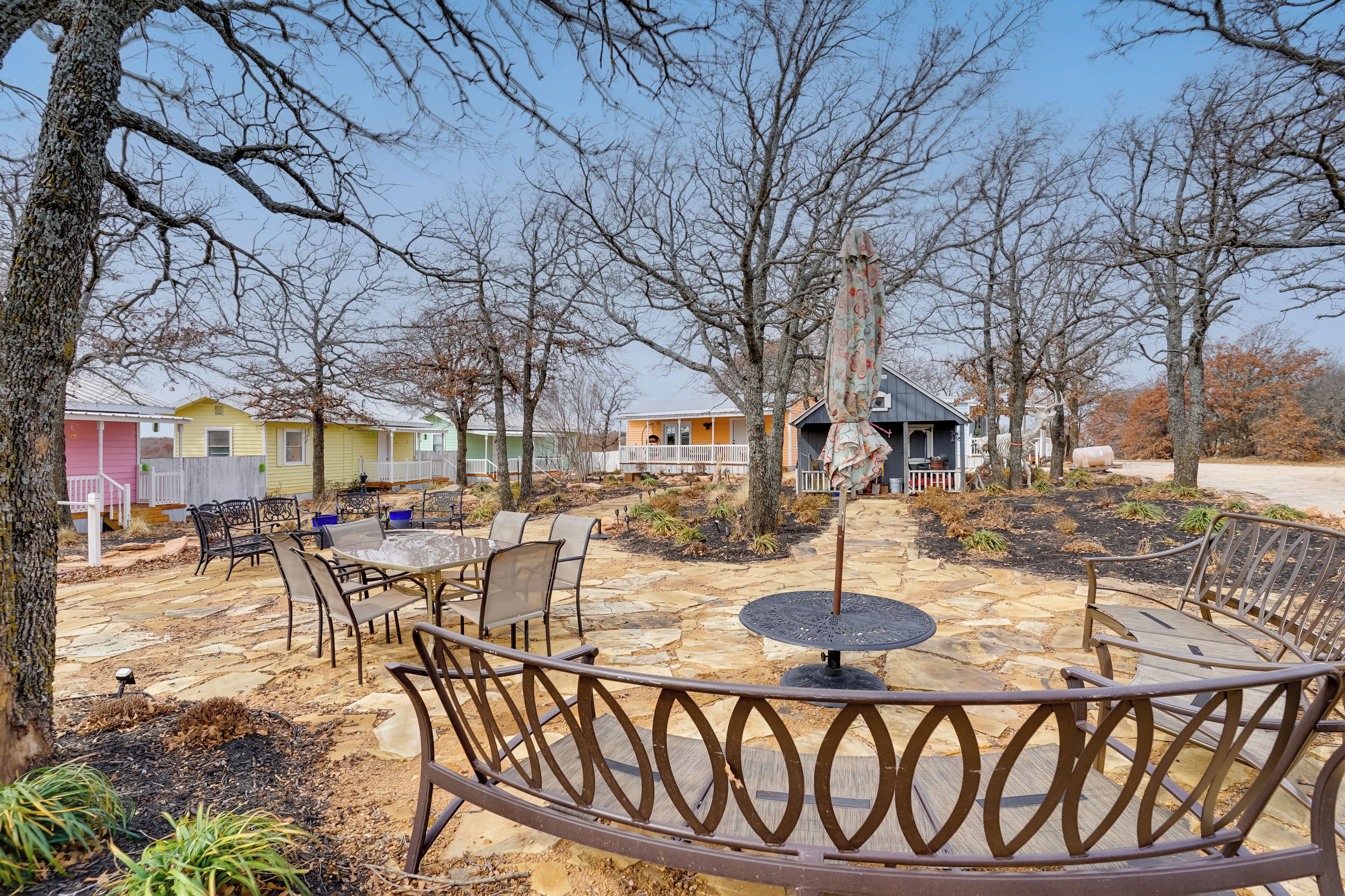 A patio area with outdoor seating, a fire pit, and a view of residential buildings in the background.