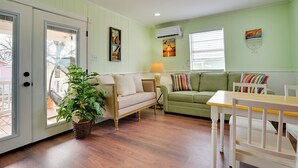 A cozy living room with a beige sofa, a green sofa, and a white table with chairs. There is a potted plant and a lamp on a side table. - Peaceful Tiny Home Getaway Near Bowie Trade Days (Bowie)