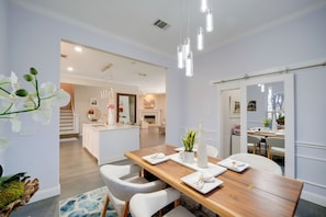 A modern dining area with a wooden table, white chairs, and a central island with a sink. - Near Joe Pool Lake! Luxe Getaway w/ Shared Pool (Cedar Hill)