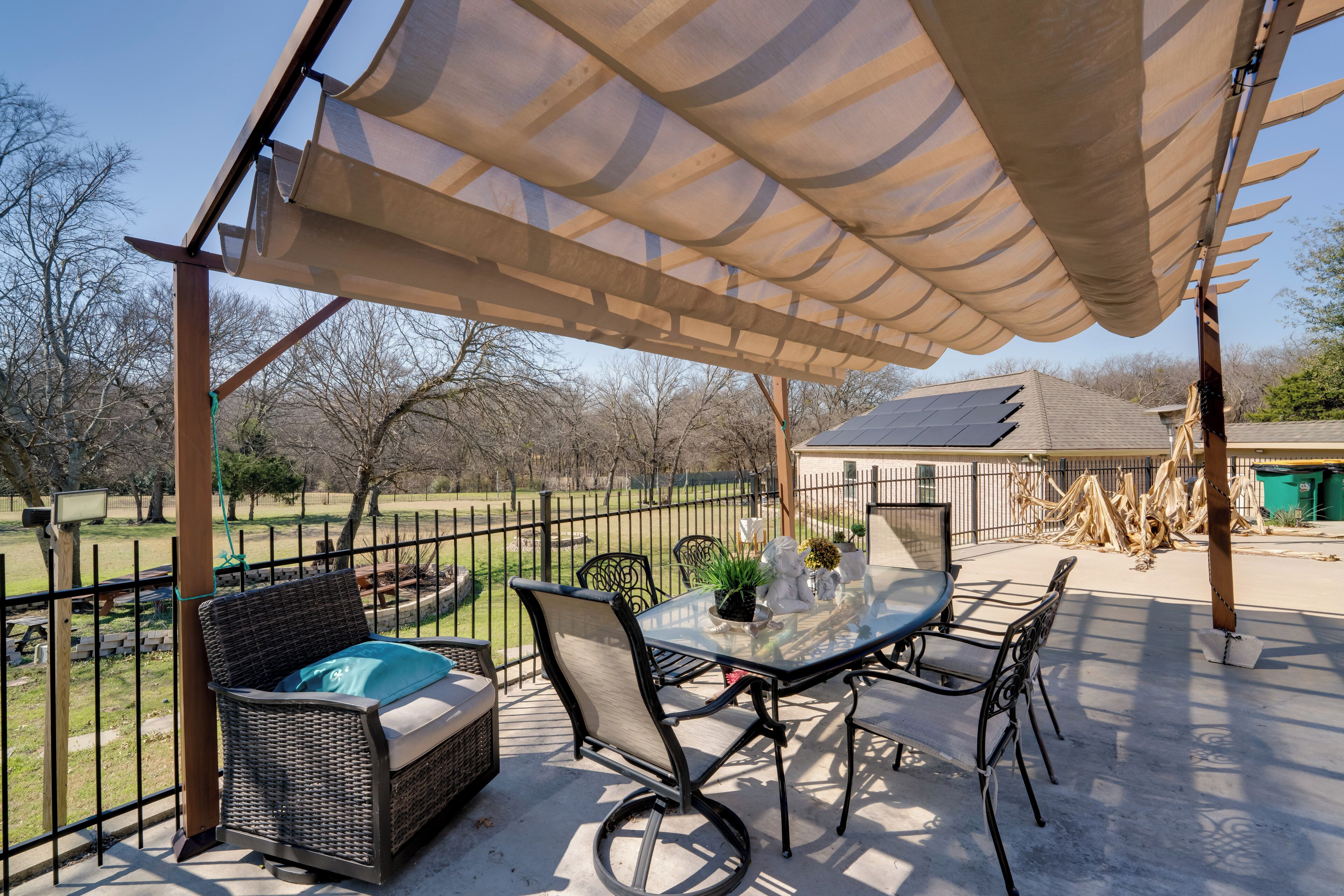 An outdoor patio with a table and chairs, a wicker sofa, and a pergola.