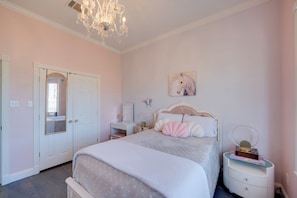 A bedroom with a bed, bedside table, dresser, and a chandelier. - Near Joe Pool Lake! Luxe Getaway w/ Shared Pool (Cedar Hill)