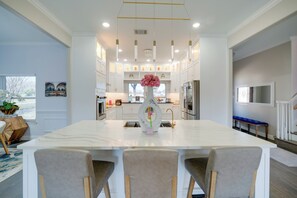 A modern kitchen with white cabinetry, a marble island, and pendant lighting. - Near Joe Pool Lake! Luxe Getaway w/ Shared Pool (Cedar Hill)