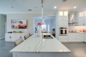 A modern kitchen with a large island, white cabinetry, and a pendant light. - Near Joe Pool Lake! Luxe Getaway w/ Shared Pool (Cedar Hill)