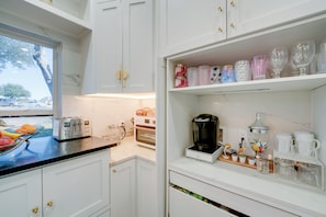 A kitchen with white cabinets, a toaster, a coffee maker, and a window with a view of the outside. - Near Joe Pool Lake! Luxe Getaway w/ Shared Pool (Cedar Hill)