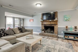Ein Wohnzimmer mit Kamin, einer Couch, einem Couchtisch und einem Fernseher.
