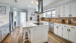Una cocina moderna con armarios blancos, una isla central y un salpicadero de ladrillo.