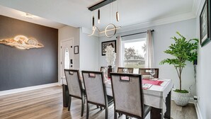 Un comedor con piso de madera, una mesa dispuesta para cuatro personas y una lámpara colgante.