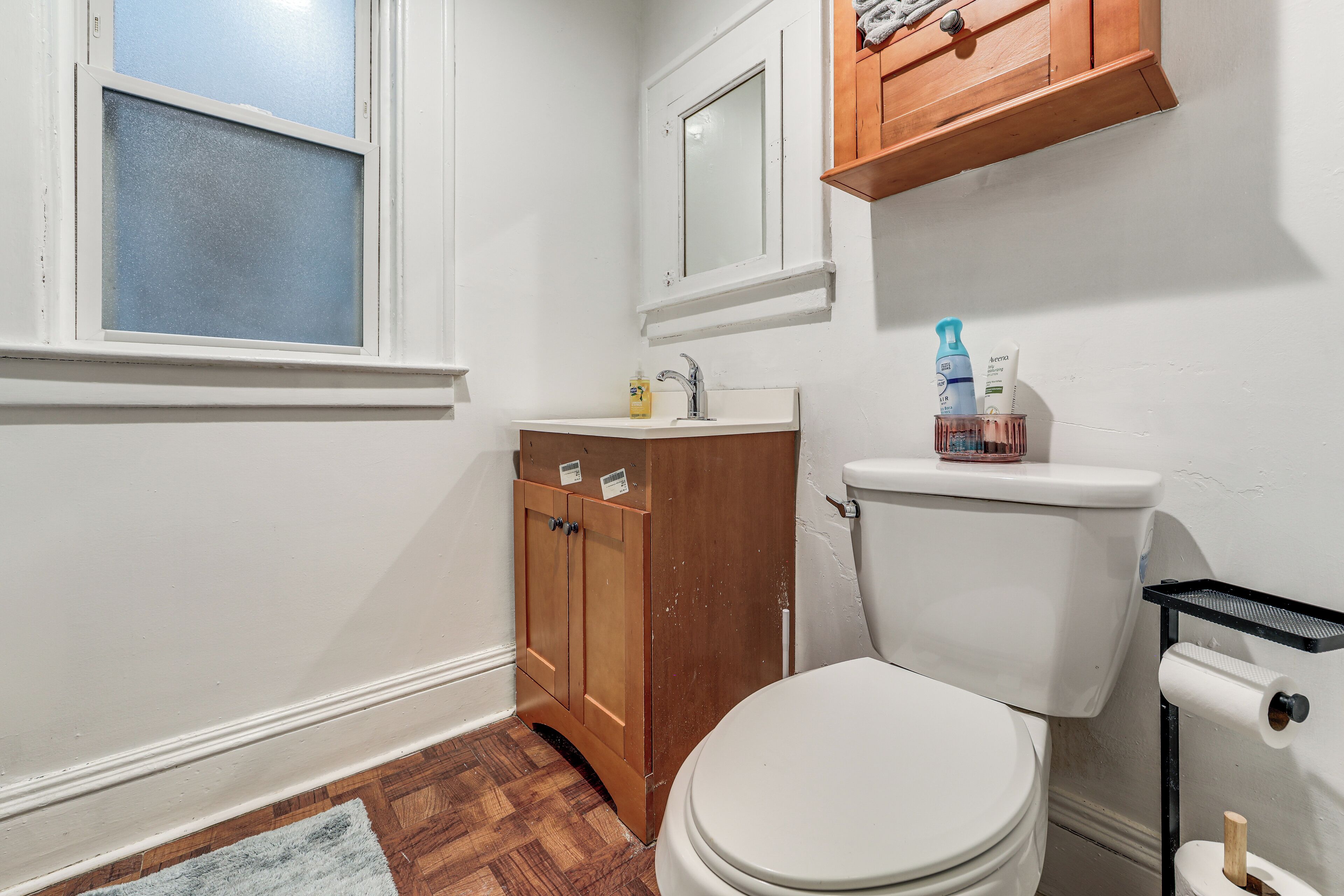 Une salle de bain avec des toilettes, un meuble en bois et une fenêtre.