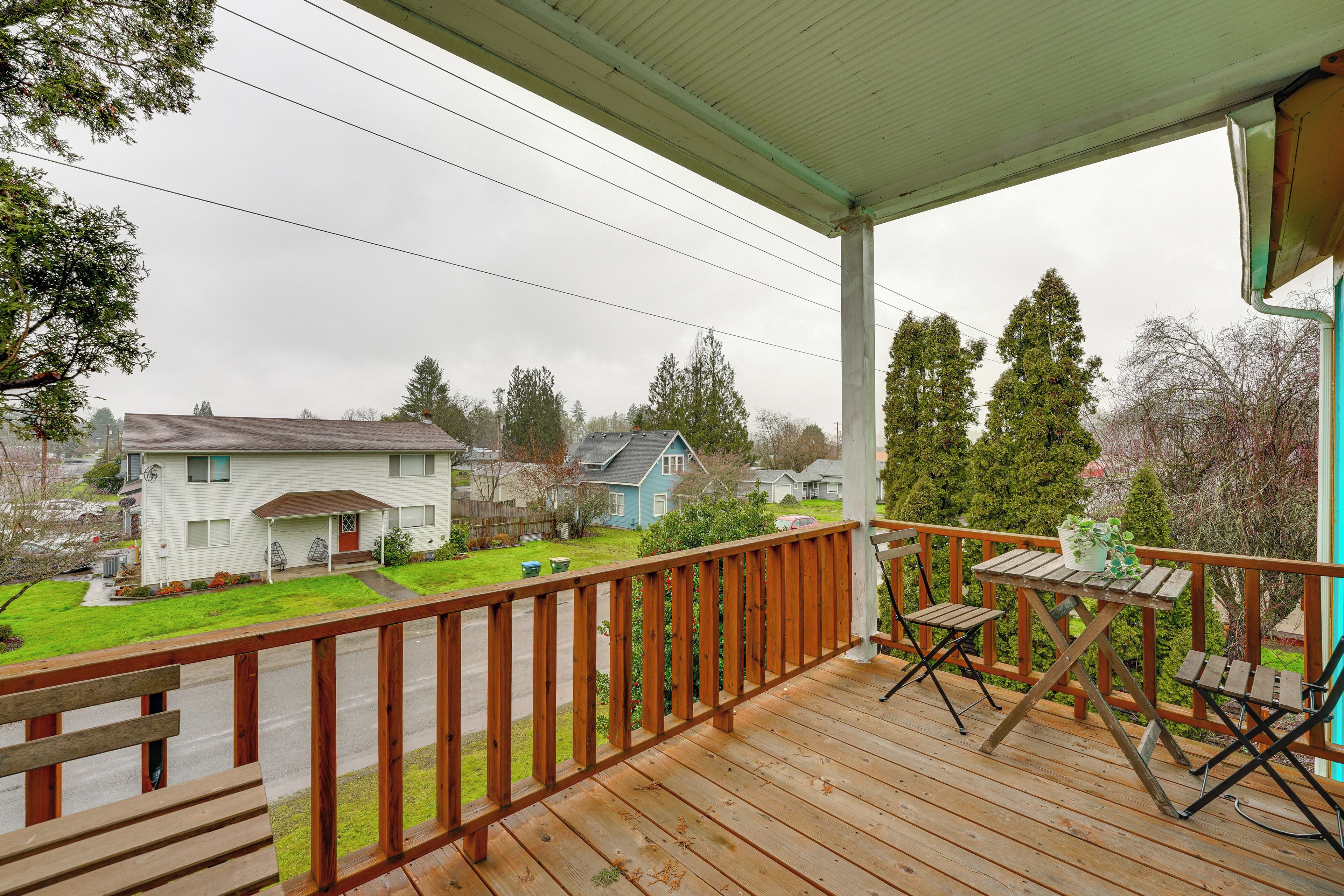 A wooden deck with a table and chairs, overlooking a residential area with houses and trees.