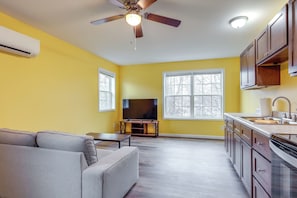 A modern kitchen with wooden cabinets, a built-in oven, and a large window providing natural light.