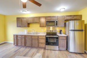 A kitchen with wooden cabinets, a stainless steel refrigerator, a microwave, and an oven.