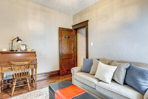 A living room with a wooden desk, a chair, a sofa with cushions, and a door. - Gateway to PA Wilds: Brockport Family Home! (Brockport)