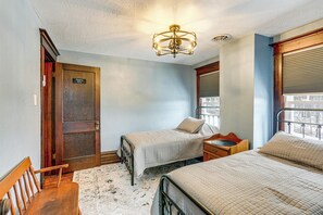 A hotel room with two beds, a wooden chair, a small wooden table, and a ceiling fan.