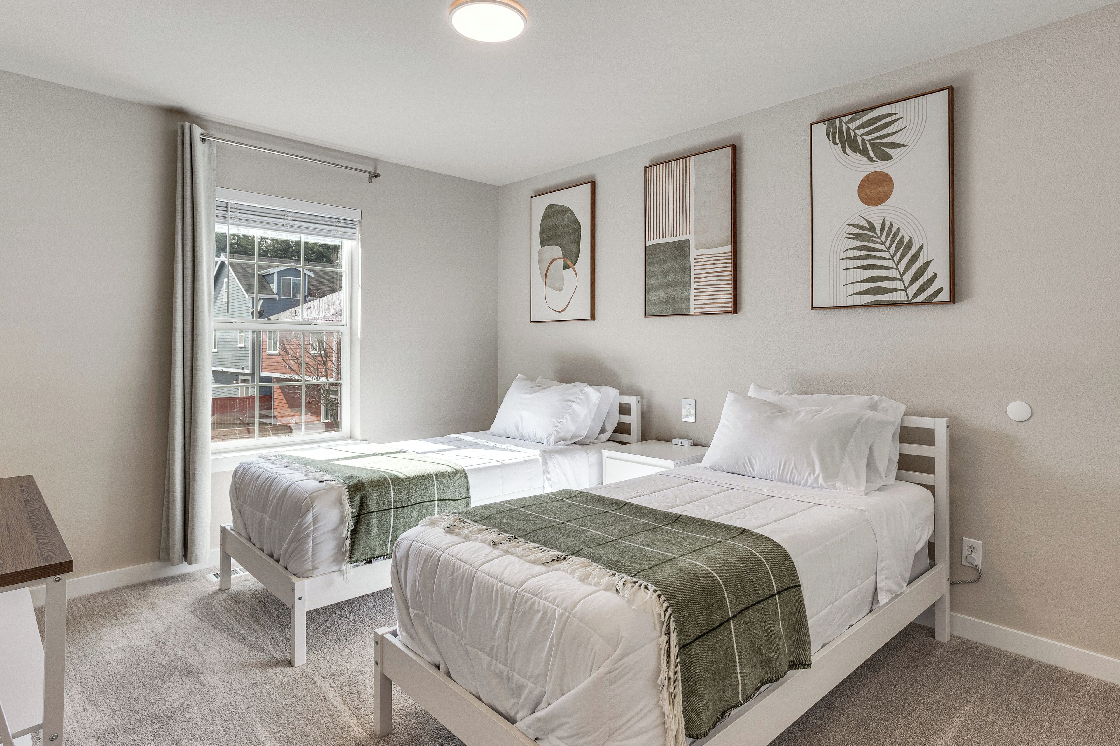 Ein Schlafzimmer mit zwei Betten, einem Fenster mit Vorhängen und Bildern an der Wand.