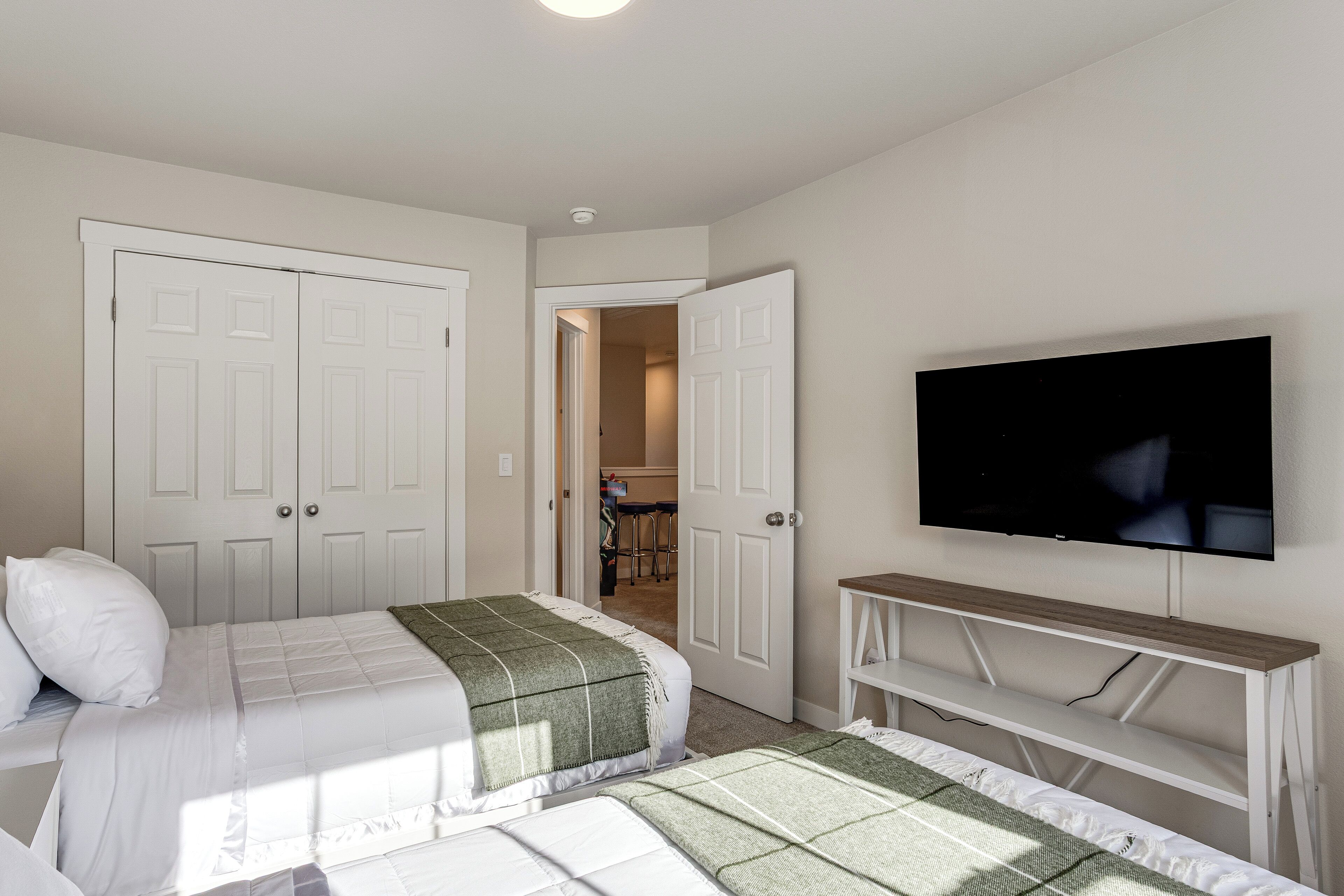 A bedroom with two beds, a TV, and a door leading to a hallway.
