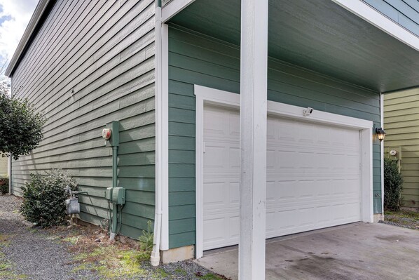 A garage with a white door, green siding, and a concrete driveway. - Bright & Modern! Family Home 11 Mi to Dtwn Tacoma (Tacoma)
