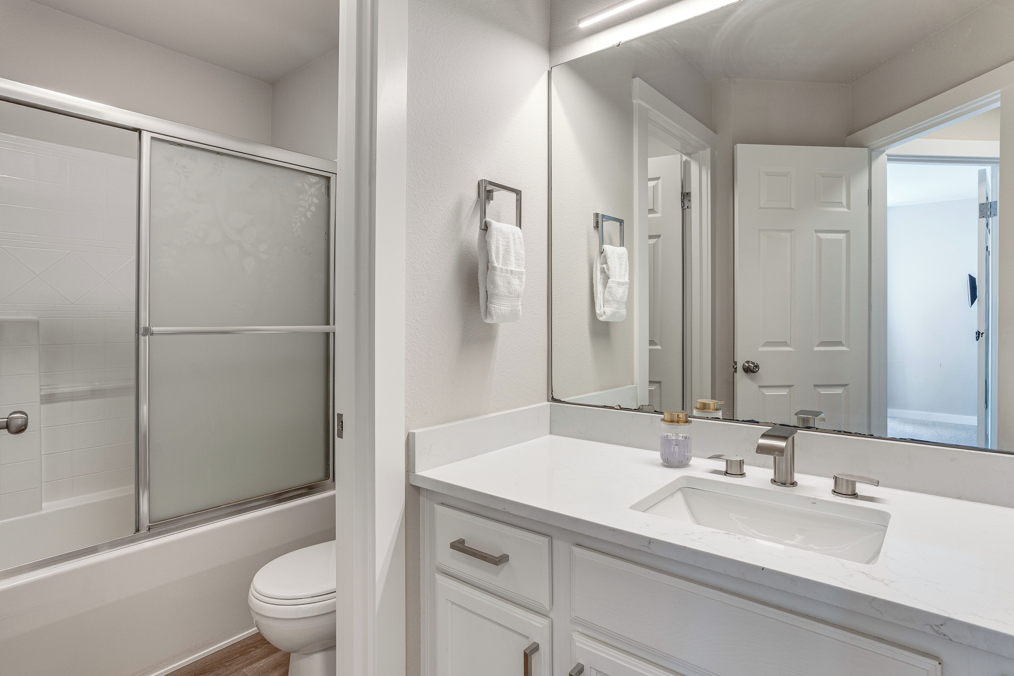 Baño con lavamanos, espejo e inodoro blancos.