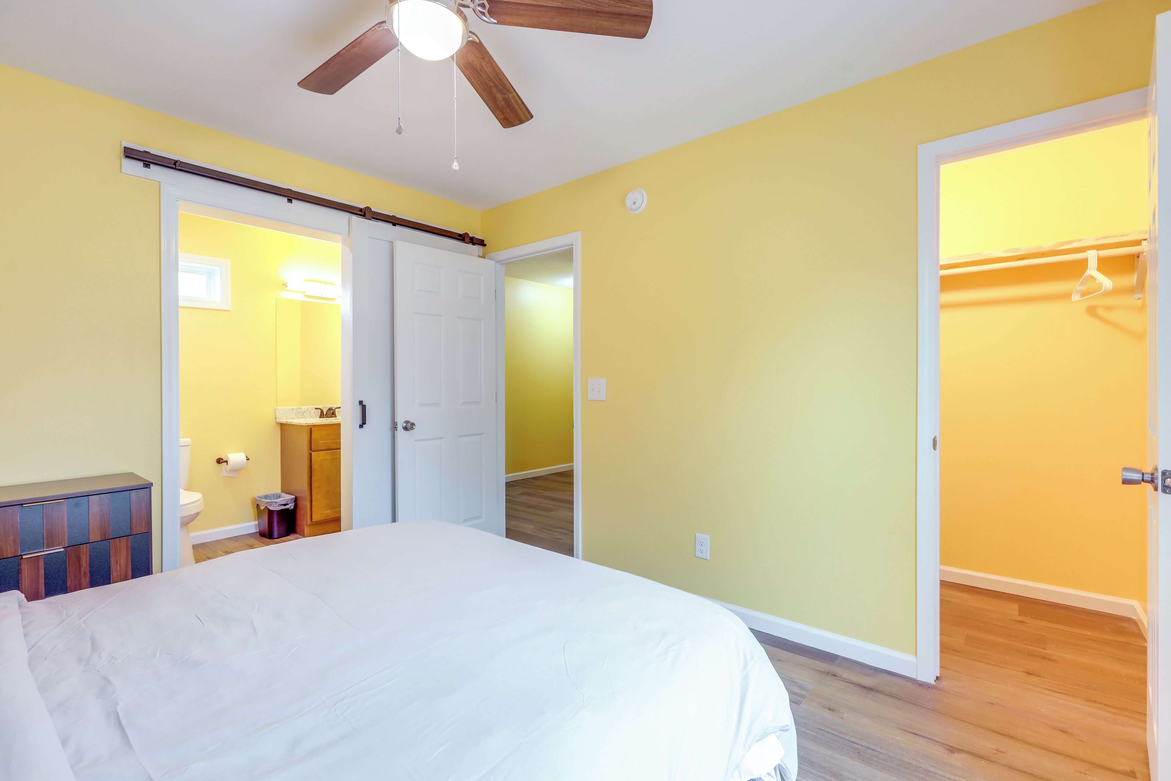 A bedroom with a bed, a ceiling fan, and a wardrobe.
