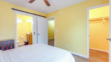 A bedroom with a bed, a ceiling fan, and a wardrobe.