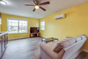 A spacious living room with a sofa, a coffee table, and a TV. - Explore Downtown Ashland! Cozy + New Apartment (Ashland)