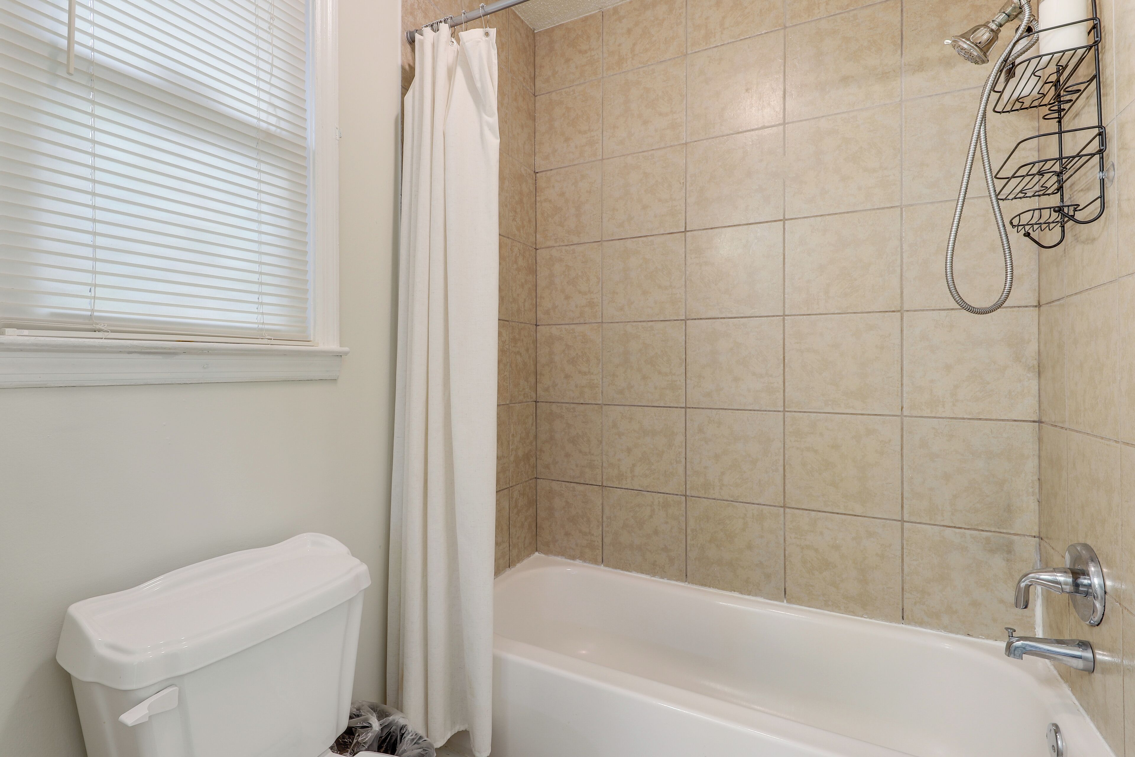 A bathroom with a bathtub, a toilet, and a shower head mounted on the wall.