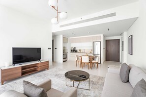 A modern living room with a flat-screen TV, a wooden entertainment unit, a round coffee table, and a sofa. - Silkhaus Modern 1bdr Marina Vista Private Beach (Dubai)