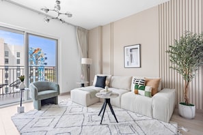 Ein modernes Wohnzimmer mit einer Couch, einem kleinen Tisch, einer Topfpflanze und Blick auf die Skyline durch große Fenster.