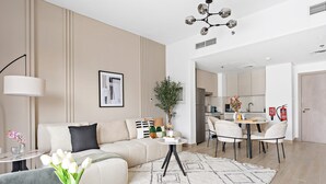Een moderne woonkamer met een bank, een eettafel en een keuken op de achtergrond.