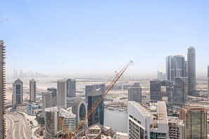 A high-rise building with a distinctive curved facade, surrounded by other modern skyscrapers and a busy waterfront. - Silkhaus High Floor in Burj Royale Stunning View (Dubai)