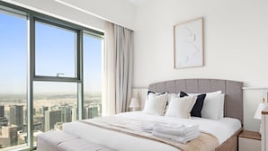 Une chambre d’hôtel moderne dotée d’un grand lit, offrant une vue sur la ville et présentant une décoration minimaliste.