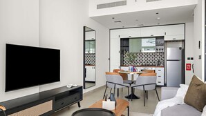 Una sala de estar moderna con un televisor de pantalla plana, una mesa de centro de madera y un sofá gris.