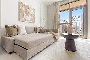 A modern living room with a beige sofa, a round coffee table, and a large window with curtains. - Silkhaus 1bdr Serene Stay in Reem Island (Abu Dhabi)