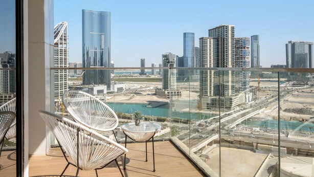 Een balkon met uitzicht op een stadsgezicht, inclusief hoogbouw en een waterpartij.